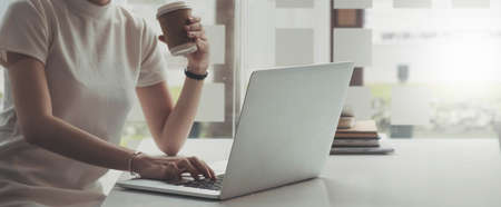 Side view of a businesswoman working on a laptop blank white screen at office. Mock up.