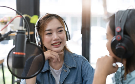 Smile two asian young woman, man radio hosts in headphones, microphone while talk, conversation,...