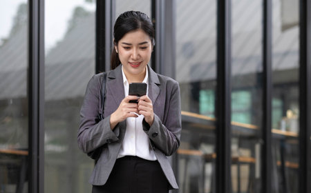 Portrait of a beautiful smiling woman using a mobile phone outdoorsの写真素材