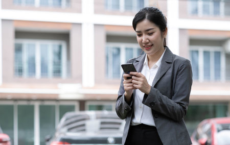 Portrait of a beautiful smiling woman using a mobile phone outdoorsの写真素材