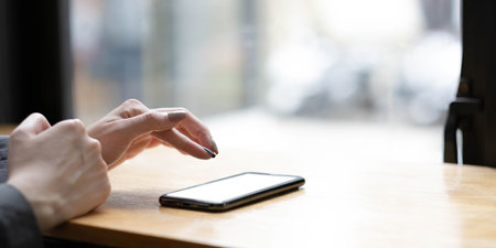 Woman holding phone with blank screen in hand on street view from window backgroundの写真素材