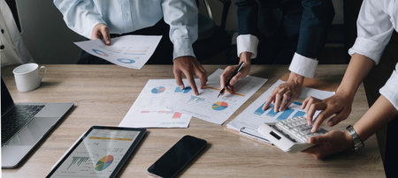Closeup of businesspeople hands pointing a pie chart together on the paperwork