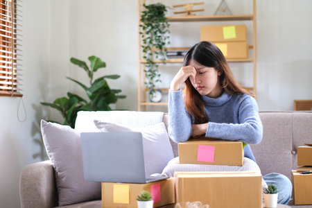 Young Asian Woman Working at home, Young Owner Woman annoyed customer and working with boring emotion. People with online shopping SME entrepreneur or freelance working concept.の写真素材