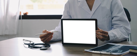 Portrait of experienced doctor woman cardiologist present modern technology white screen tablet she use consult patients wear white coat uniform stethoscope in examination room.の写真素材