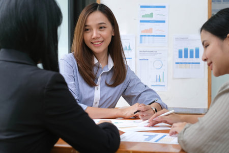Two young Asian businesswomen show joyful expression of success at work smiling happily with a laptop computer in a modern office.の写真素材