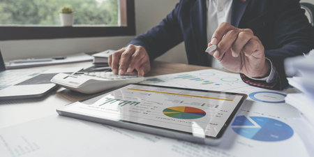 Close up Businessman  using calculator and ldigital tablet for calaulating finance, tax, accounting,...