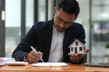 House model with agent business man signs a purchase contract and use calculator buy mortgage for a home, buy and sell home insurance concerning mortgage loan Real estate concept.の写真素材