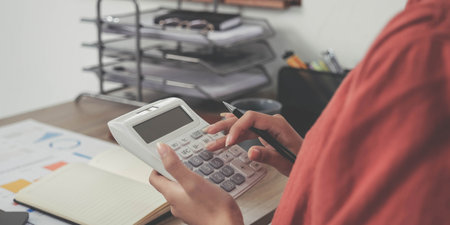 Business woman using calculator and laptop for do math finance on wooden desk in office and business...