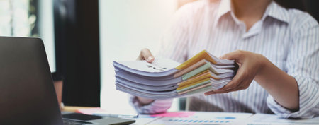 Business Documents concept : Employee woman hands working in Stacks paper files for searching and...