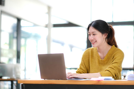 Asian Businesswoman Using laptop computer and working at office with calculator document on desk, doing planning analyzing the financial report, business plan investment, finance analysis concept.の写真素材