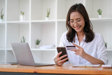 Young Asian businesswoman enjoy shopping online using credit card at a coffee shop.