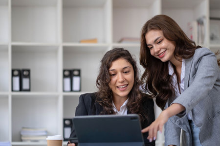 Two young Asian business woman talk, consult, discuss working with new startup project idea presentation analyze plan marketing and investment in the office.の写真素材