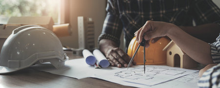 Builder two asian young engineer man and architect woman are discussing construction from a plan to follow the project to build an industrial plant at site. Worker concept.の写真素材