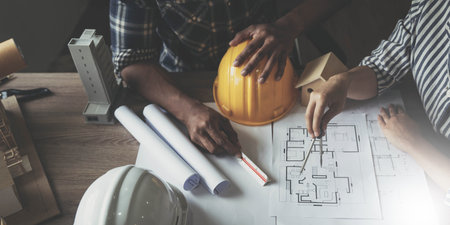 Builder two asian young engineer man and architect woman are discussing construction from a plan to...