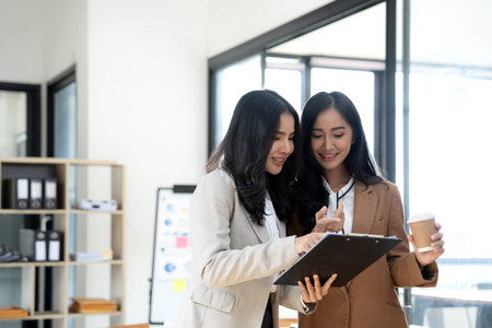 Attractive young asian woman using laptop computer while standing in a office.