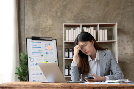 asian woman thinking hard concerned about online problem solution looking at laptop screen, worried serious asian businesswoman focused on solving difficult work computer taskの写真素材