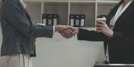 Two Asian businesswomen are shaking hands in the office. business cooperation, business dealing,...