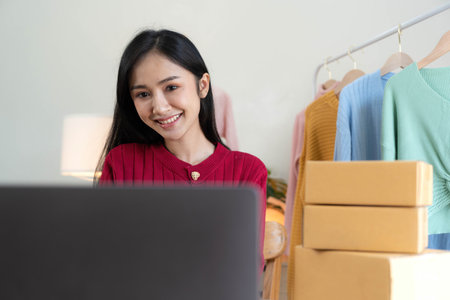 Portrait of Starting small businesses SME owners, Asian woman check online orders Selling products working with boxs freelance work at home office, sme business online small medium enterpriseの写真素材