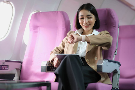 Attractive caucasian female passenger of airplane sitting in comfortable seat while working at modern laptop computer with mock up area using wireless connection on boardの写真素材