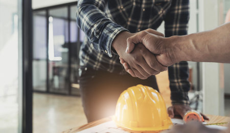 Engineers or architecture shaking hands at construction site for architectural project, holding safety helmet on their hands.の写真素材
