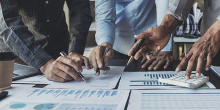 Business People Meeting using laptop computer,calculator,notebook,stock market chart paper for...