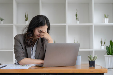 Portrait of serious young businesswoman accountant in formal wear sitting at her work place and use laptop, summarizing taxes, planning future investments, accounting at office.の写真素材