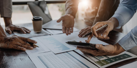 Business People Meeting using laptop computer,calculator,notebook,stock market chart paper for...