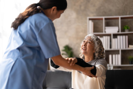 Young caregiver helping senior woman walking. Nurse assisting her old woman patient at nursing home. Senior woman with walking stick being helped by nurse at home.の写真素材