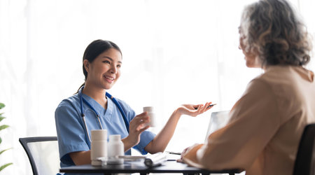 Asian Senior elderly female patient consult with physician nurse at nursing home care. Caregiver therapist pharmacist girl hold medicine pills bottleの写真素材