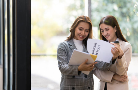 Two Asian businesswomen discussing, sharing their business ideas, reviewing financial report...