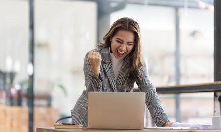 Pretty Asian businesswoman sitting on a laptop And the work came out successfully and the goal was achieved, happy and satisfied with her.の写真素材