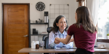 Middle aged female pediatrician listening to young womans complaints with health problems And write down on the medical history paper during the treatment. health conceptの写真素材