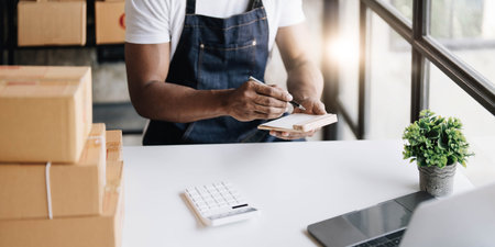 Start-up small business SME owner man entrepreneurs, write the address on receipt box and check online orders, prepare to pack boxes, selling online, e-commerce, SME business online concept.の写真素材