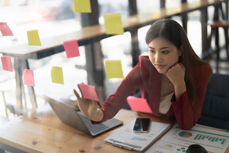 Young businesswoman creative team using  notes in glass wall to writing strategy business plan to development grow to success.の写真素材