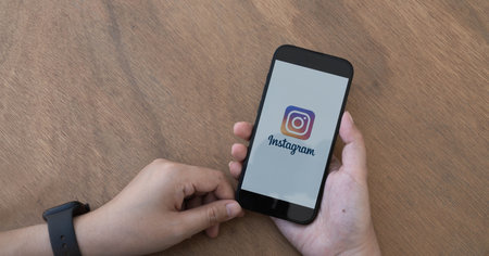 CHIANG MAI, THAILAND - FEB 11 2023: A woman holds Apple iPhone 14 with Instagram application on the screen at cafe. Instagram is a photo-sharing app for smartphones.のeditorial素材