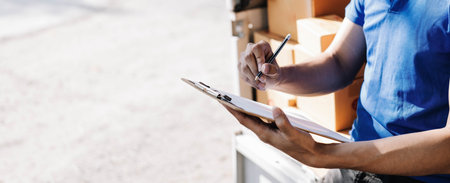 Closeup asian young delivery man courier in uniform hold documents clipboard and box checking list...