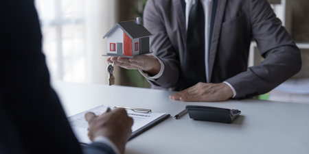 Real estate agent is discussing and explaining the terms of the home purchase contract. Businessman signing a contract agreement, mortgage, rent, lease, home insurance.の写真素材