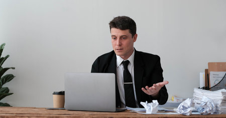 Perplexed, puzzled handsome businessman looking at laptop screen at workplace in office. Young CEO...
