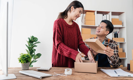 Young asian people couple Male and female small business owner checking online orders and packing...