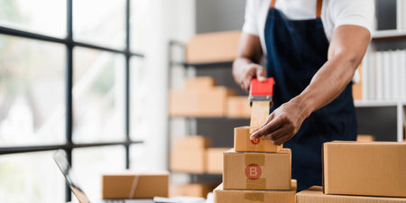 Photo of young entrepreneur man packing he goods while sitting in table comfortable sitting room as...