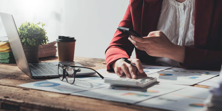 Business woman using calculator for do math finance on wooden desk in office and business working background, tax, accounting, statistics and analytic research concept.の写真素材