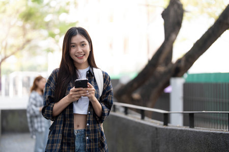 young happy attractive asian student smiling and looking at camera with friends on outdoor university background. Asian woman in self future education or personalized learning concept.の写真素材