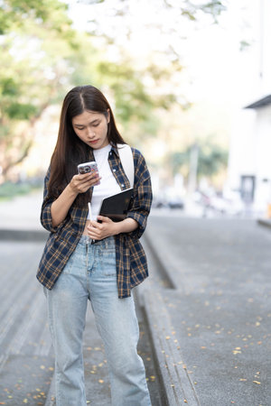Female college students happily holding laptops outdoors after school on campus. when the sun goes down the horizon with warm lightの写真素材