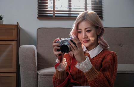 Young beautiful Asian woman relaxing in living room at home, reading books, drinking coffee and using phone in the morning with happy feelingの写真素材