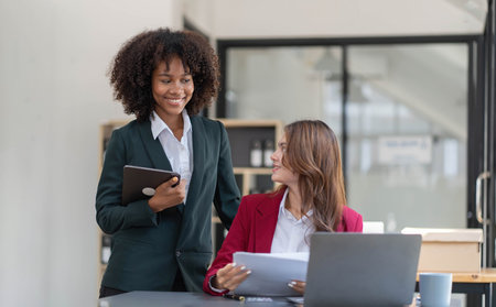 Two business people talk project strategy at office meeting room. Businessman discuss project planning with colleague at modern workplace while having conversation and advice on financial data report.の写真素材
