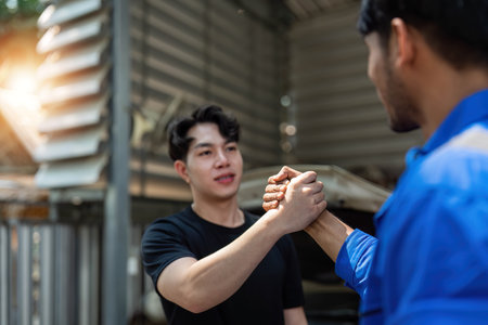 Two car mechanic team shaking hand at automobile service center. Repair service concept. Car repair and maintenance. Car mechanic working at automotive team service centerの写真素材