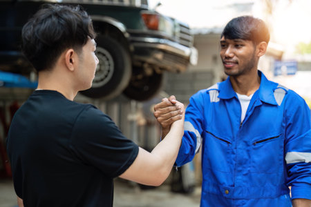 Two car mechanic team shaking hand at automobile service center. Repair service concept. Car repair and maintenance. Car mechanic working at automotive team service centerの写真素材
