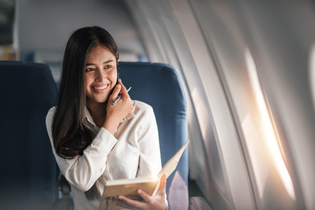 Asian young woman using smartphone and take notes in a notebookの写真素材