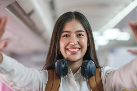 Portrait of an Asian woman taking a selfie or capturing memories while waiting for an economy class flight. Travel concept, vacations, tourismの写真素材