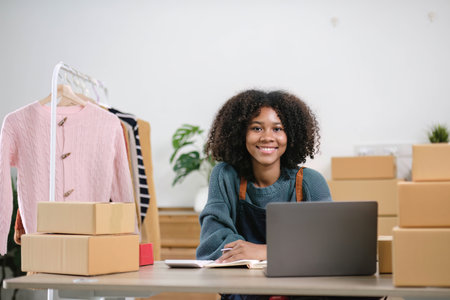 Young woman freelancer sme business online shopping look at camera with cardboard box on table at home - Business online shipping and delivery conceptの写真素材